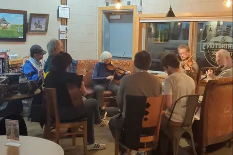 A group of people playing musical instruments together inside a room.