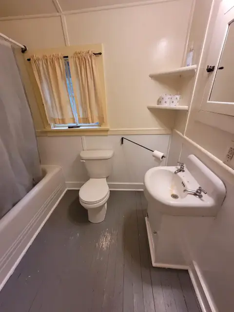 An interior view of a small bathroom with a tub, toilet, and sink.