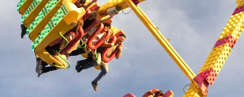 People riding a carnival amusement ride against a bright sky.