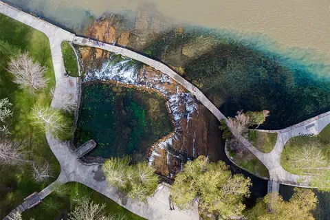 An aerial view shows a park walkway curving around a waterfall and pool.