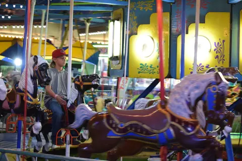 A child rides a carousel horse at an amusement venue.
