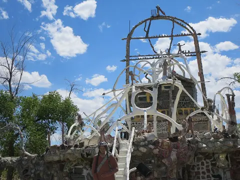 An elaborate folk art structure and statues against a blue sky with clouds.