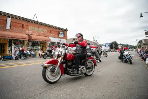 A group of motorcyclists ride down a street during an event.