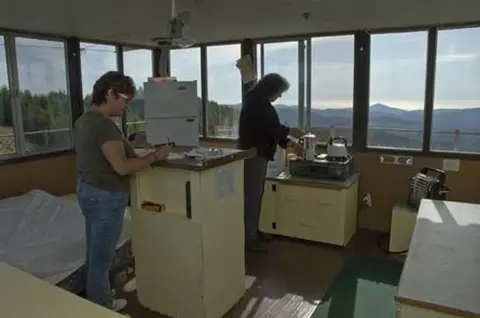 Two people inside a fire lookout tower.
