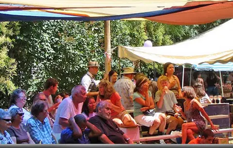 A crowd of people sitting under canopies outdoors.