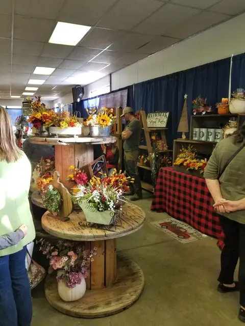 People browse autumn and holiday craft displays inside a building.