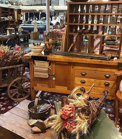 A collection of antique wooden furniture and decorative items inside a store.