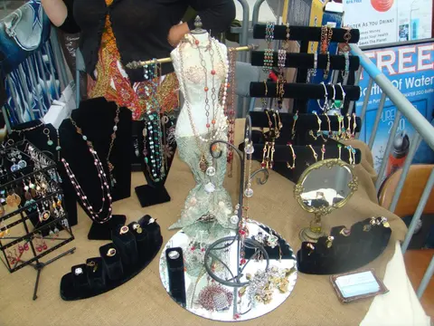 A display of jewelry items, including necklaces, earrings, and rings on a table at an outdoor market.