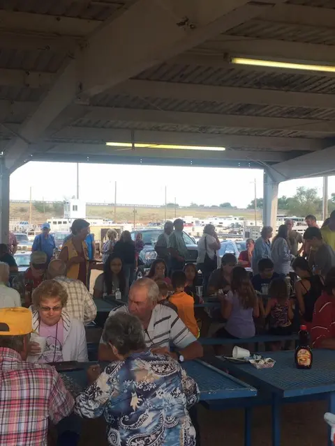 People gathered at tables under an open-air pavilion.