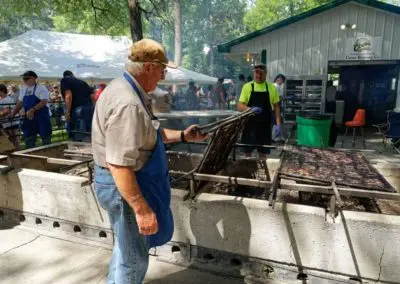 People grilling food outdoors at a public event.