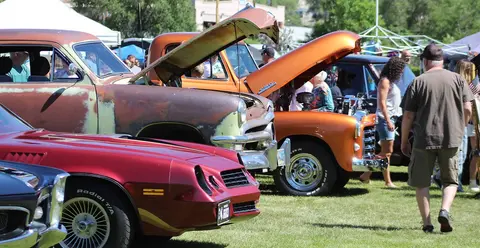 A row of classic cars on display at an outdoor car show.
