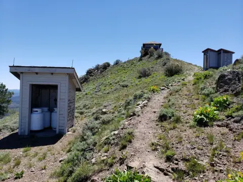 A trail leading up a grassy hill towards a structure on the summit.