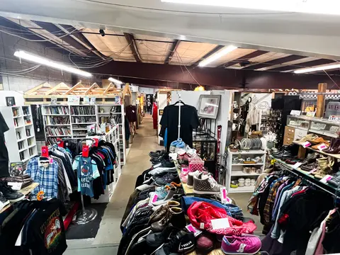 An interior view of a thrift store with clothing racks and shelves.