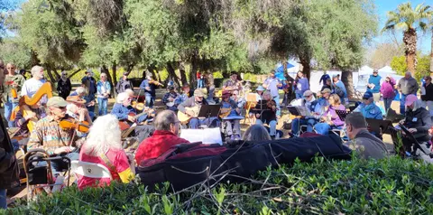 A group of people playing musical instruments together outdoors.
