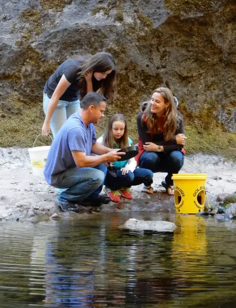 A family pans for gold in a stream.