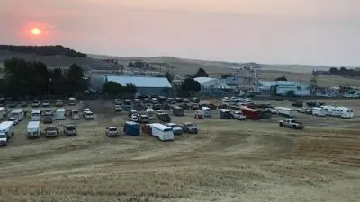 A wide shot of a parking area and fairgrounds at sunset.