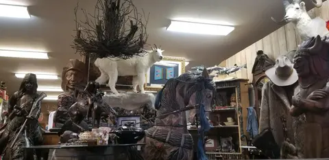 The interior of a shop displaying sculptures, taxidermy, and rustic decor.