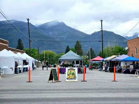 A street market with tents set up against a backdrop of mountains.
