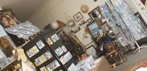 An interior view of a shop filled with vintage license plates, pictures, boots, and western memorabilia.