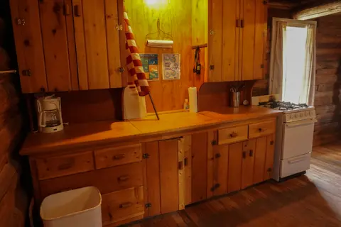 A rustic wooden kitchen interior with cabinets and a stove.