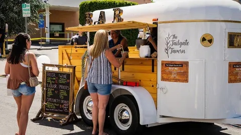 Customers order drinks from a converted horse trailer bar.