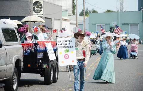 People participating in a parade with floats and historical costumes.