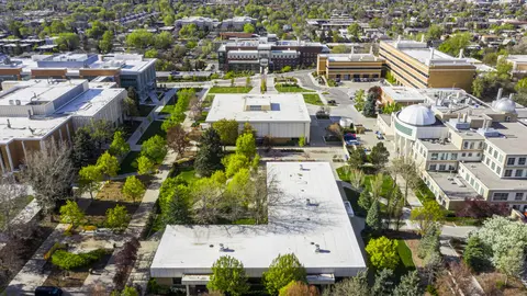 An aerial view shows a university campus with buildings and green spaces.