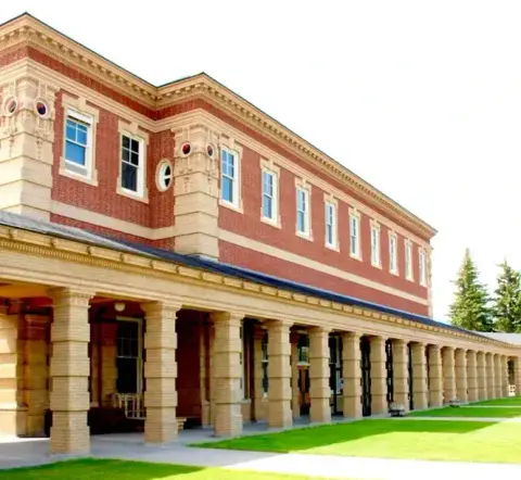 An exterior view of a brick building with a long colonnade.