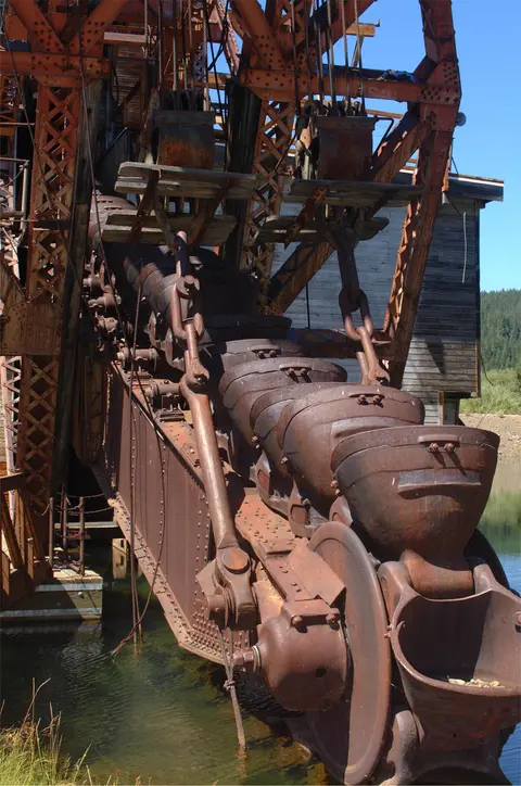 A close-up view of the bucket line and metal framework of a historic gold dredge.