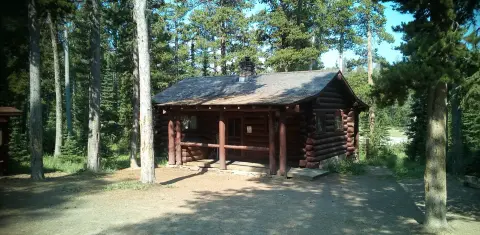 A log cabin surrounded by trees in a forested area.