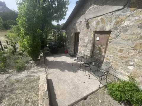 An exterior view of a stone building with a small patio and seating area.