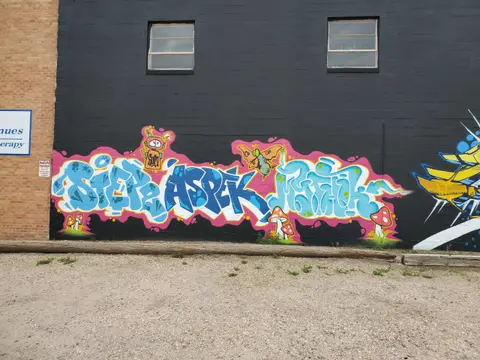 Colorful graffiti is painted on the black exterior wall of a building.