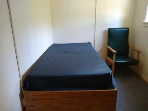 A small room with a bed and a green armchair.