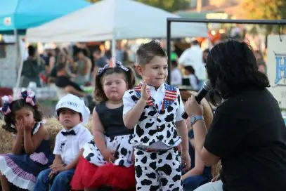 Young children dressed in festive outfits at an outdoor event.