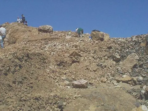 People climbing and exploring a rocky hillside.
