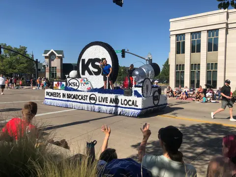 A parade float moves down a street with people watching.