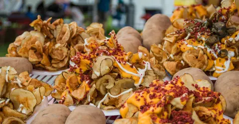 A close-up view of loaded potato chips with toppings and whole potatoes.