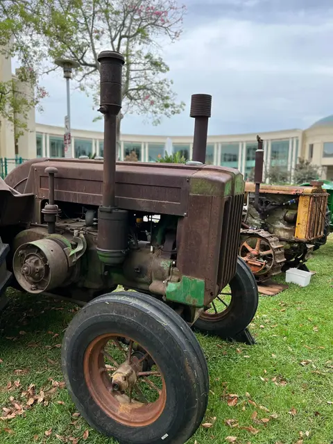 Old rusty tractors parked on a grassy lawn.