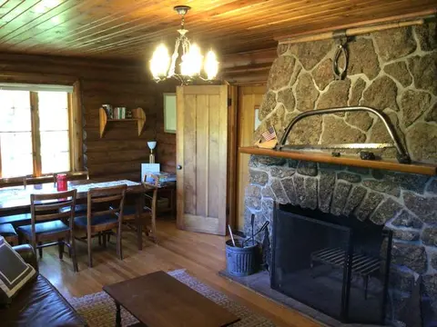 Interior of a rustic cabin featuring a stone fireplace and wooden walls.