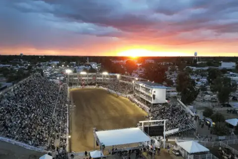 Aerial view of an outdoor arena filled with a large crowd at sunset.