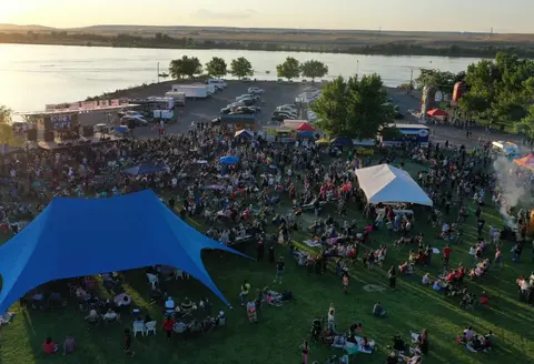 An aerial view of an outdoor crowd gathered near a body of water for an event.