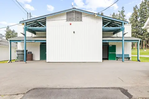 Exterior view of a white building with teal supports and green doors.