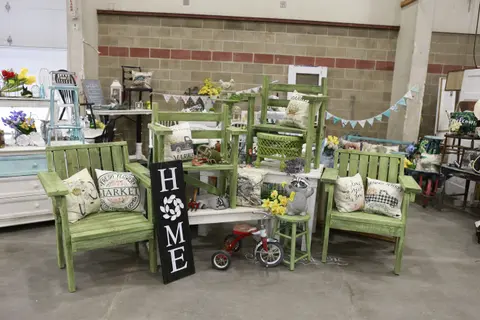 A display of home decor items, including green wooden chairs and a sign that reads HOME.
