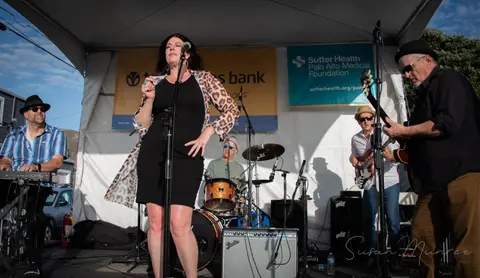 A band performs on an outdoor stage under a tent.