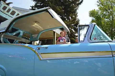 A light blue classic convertible with its hardtop roof partially raised.