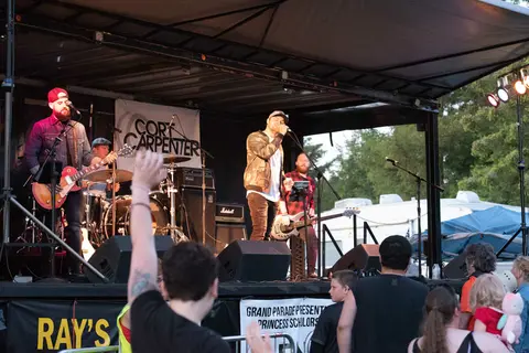 A band performs on an outdoor stage for a crowd.