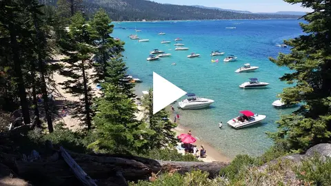A scenic view of a beach with numerous boats anchored in clear blue water.