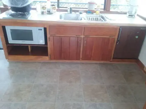 A kitchen counter with wooden cabinets and tile flooring.