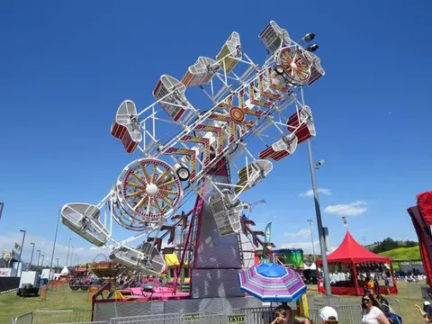 A large amusement park ride operates against a blue sky.