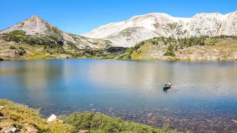A scenic view of a mountain lake with people canoeing.